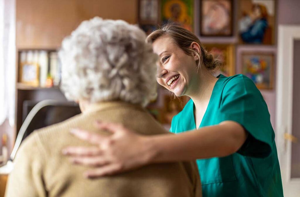 A volunteer playing cards with senior residents at a common room table, smiling and engaging in conversation.