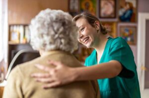 A volunteer playing cards with senior residents at a common room table, smiling and engaging in conversation.