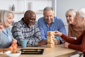 Older adults seated together at a bright dining table while a caregiver reviews a daily activity schedule.